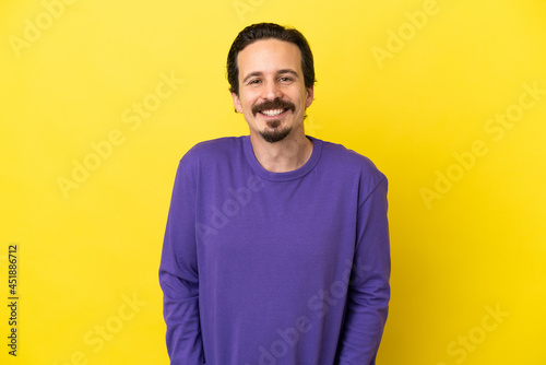 Young caucasian man isolated on yellow background laughing