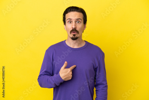 Young caucasian man isolated on yellow background pointing to oneself © luismolinero