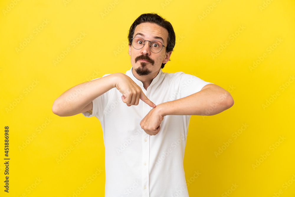 Young caucasian man isolated on yellow background making the gesture of being late Young caucasian man isolated on yellow background making the gesture of being late