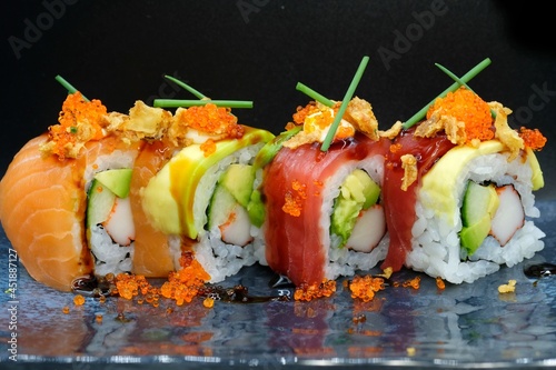 Mix different sushi with salmon, tuna, and surimi served on grey plate with dark background