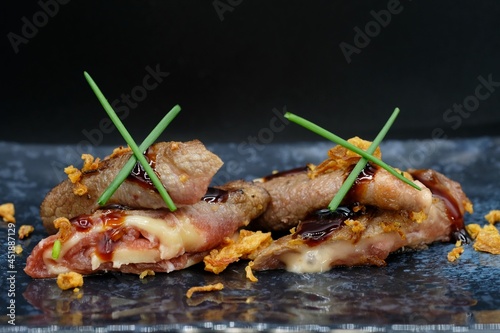 Japanese beef rolls teriyaki filled with cheese served on a grey plate with dark background