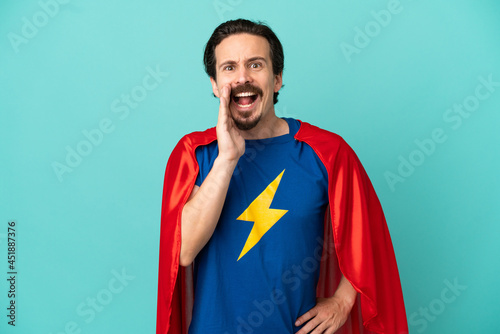 Super Hero caucasian man isolated on blue background shouting with mouth wide open