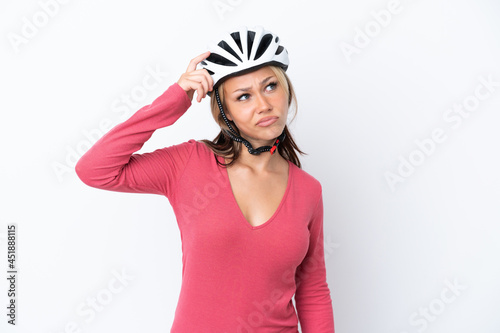 Young Russian woman wearing a bike helmet isolated on white background having doubts and with confuse face expression © luismolinero