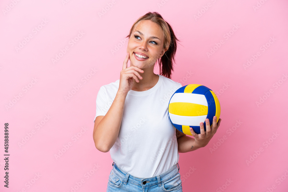 Young Russian woman playing volleyball isolated on pink background thinking an idea while looking up