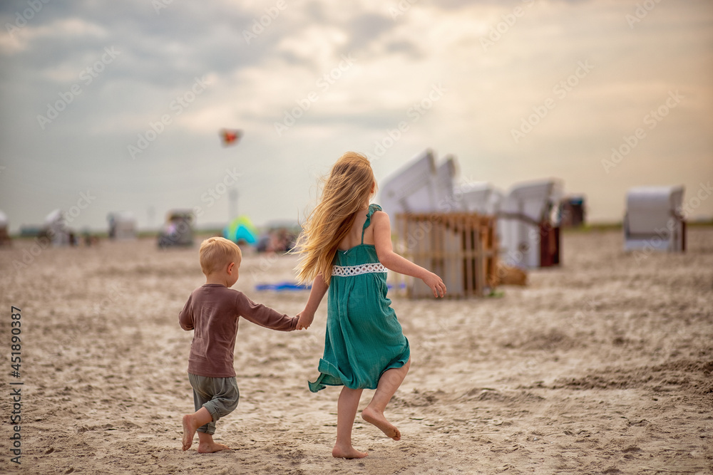 little boy and girl run in the summer along the seashore, holding hands. Brother and sister in natural clothes. Tourism, vacations, traveling with children, sun protection and safety. little boy and girl run in the summer along the seashore, holding hands. Brother and sister in natural clothes. Tourism, vacations, traveling with children, sun protection and safety.