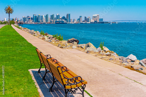 A park bench sits in a viewing area along the water and in front of the San Diego skyline in Southern California