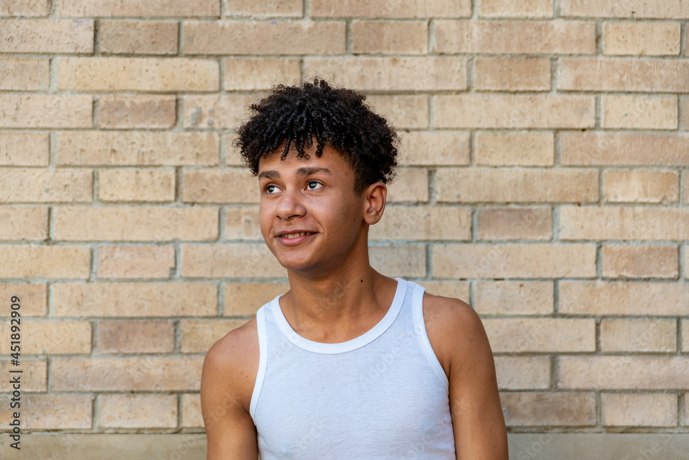 Afro latin male teenager smiling against a wall Afro latin male teenager smiling against a wall