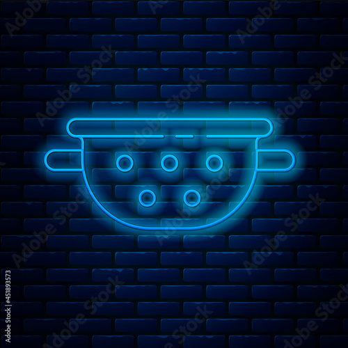 Glowing neon line Kitchen colander icon isolated on brick wall background. Cooking utensil. Cutlery sign. Vector