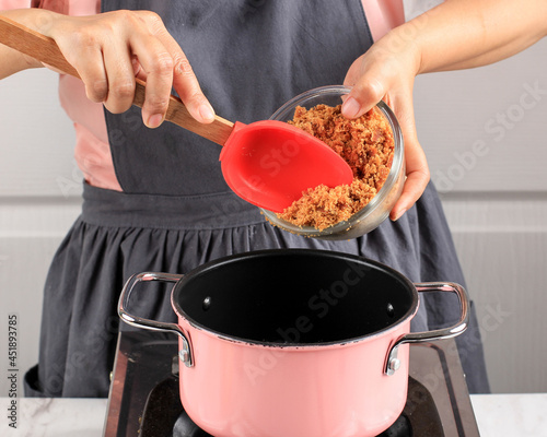 The cook girl pours brown cane sugar into a metal bowl. Cooking sweets in the kitchen making dessert, like Kolak, Bubur Sumsum for Ramadan photo