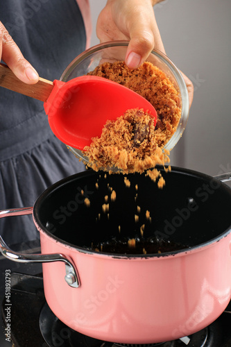 Blurry Focus, Female Chef Making Palm Sugar Syrup, Add Chopped Palm Sugar to the Pan with Boiling Water, Cooking Process Making Kolak photo