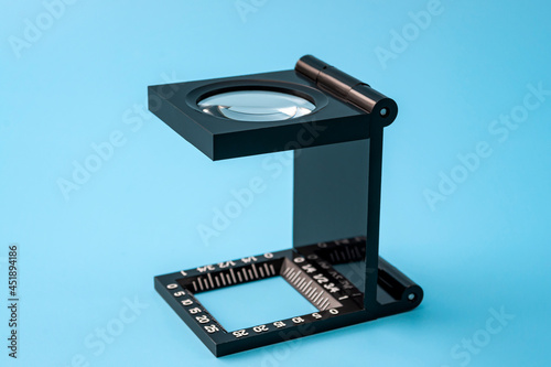 Quality control and printing industry inspection tools concept with linen test magnifier lens tool isolated on blue background