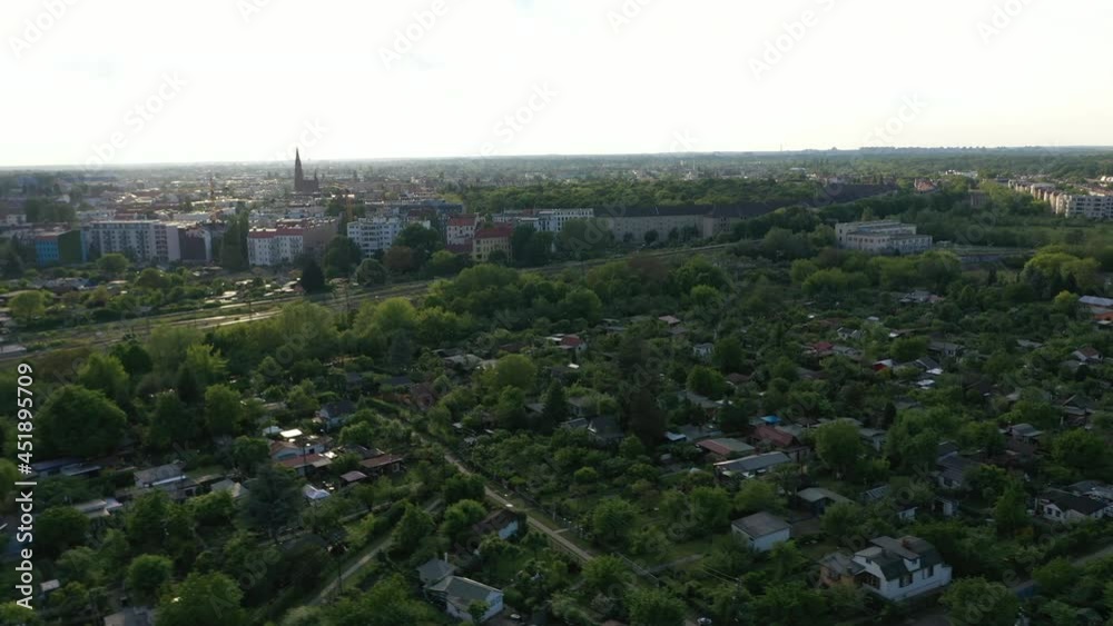 Fly above block of allotment gardens next by railway tracks. Revealing urban neighbourhood. View against afternoon sunshine. Berlin, Germany Fly above block of allotment gardens next by railway tracks. Revealing urban neighbourhood. View against afternoon sunshine. Berlin, Germany