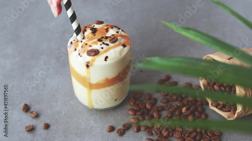 Ice coffee in the glass topped whipping cream with coffee beans. Cold summer drink.