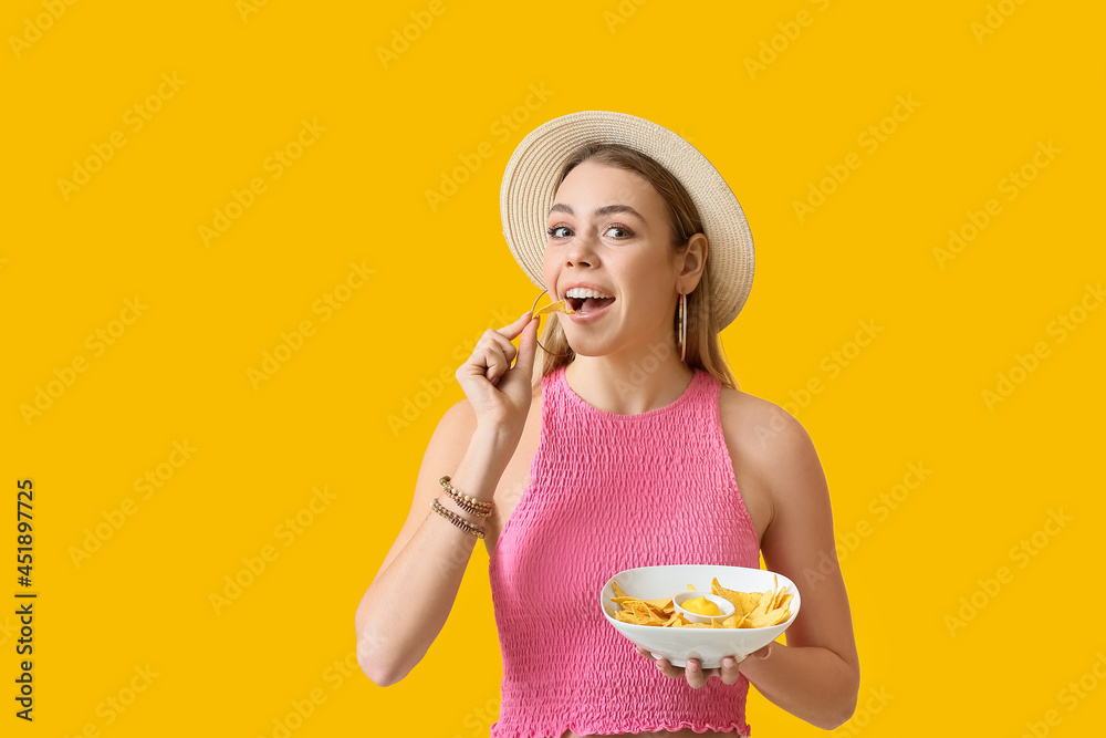 Beautiful young woman eating tasty nachos on color background Beautiful young woman eating tasty nachos on color background