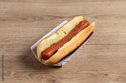 A plain hotdog in a bun on a wooden table