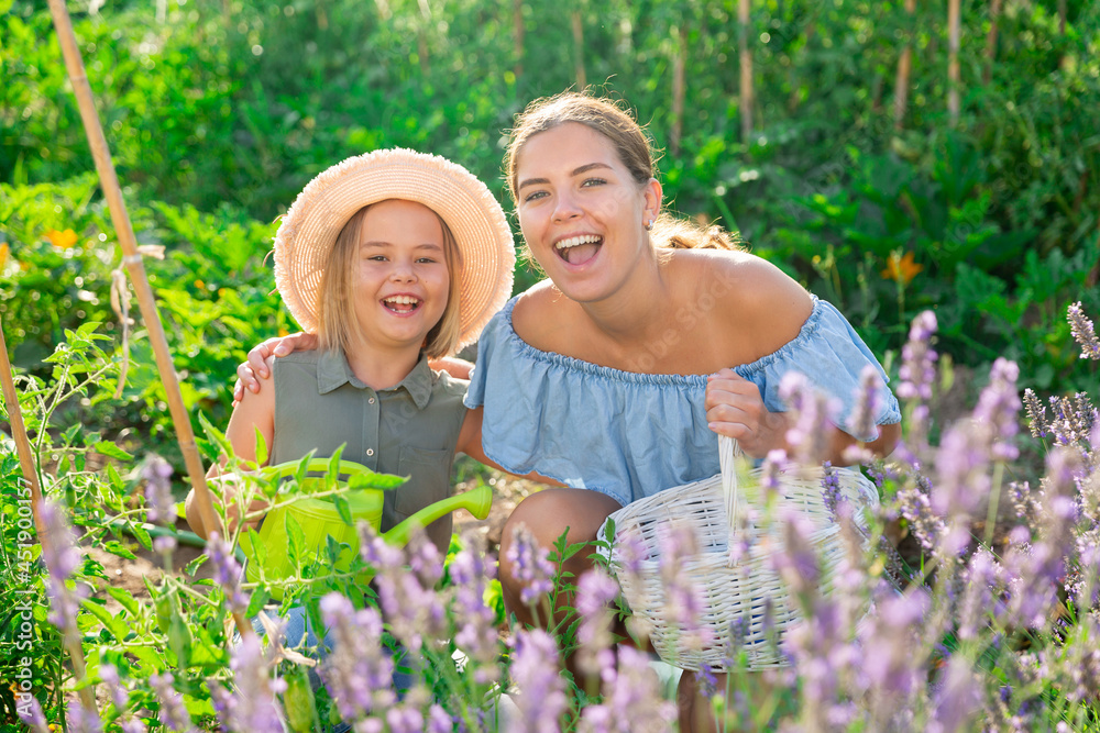 Mom and daughter spending a great time together in the garden beside lavender shrub