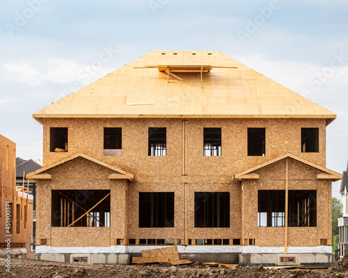 A residential frame house construction project showing the engineered truss roof rafters and oriented strand chip board engineered wall sheathing