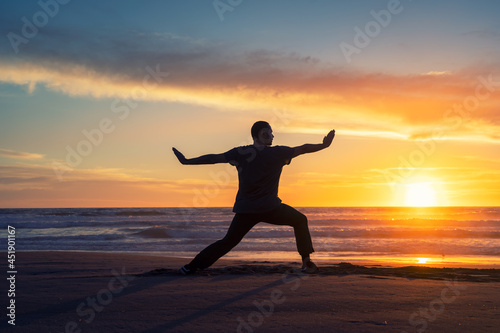 silhouette of a person on the beach doing yoga or exercise at beautiful sunset 