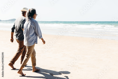 Quadro em tela Romantic Senior couple strolling happily along the beach in the warm sunshine