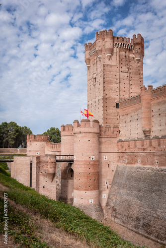 Tower and entrance of the castle of La Mota in Valladolid, Spain with a beautiful blue sky with white clouds.
