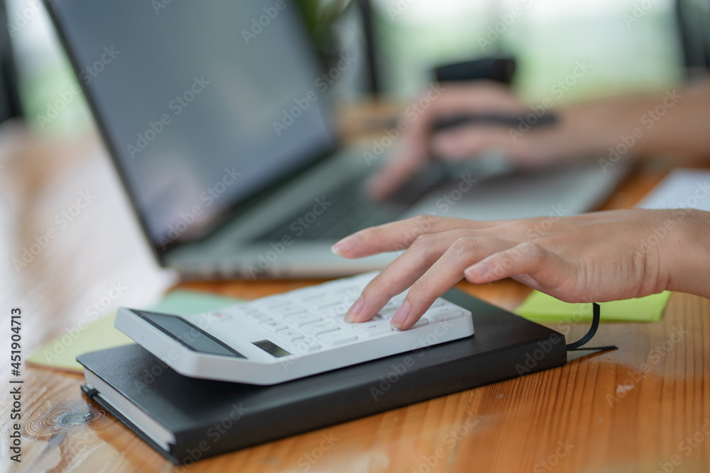 Close-up of a businesswoman using a white calculator. Close-up of a businesswoman using a white calculator.
