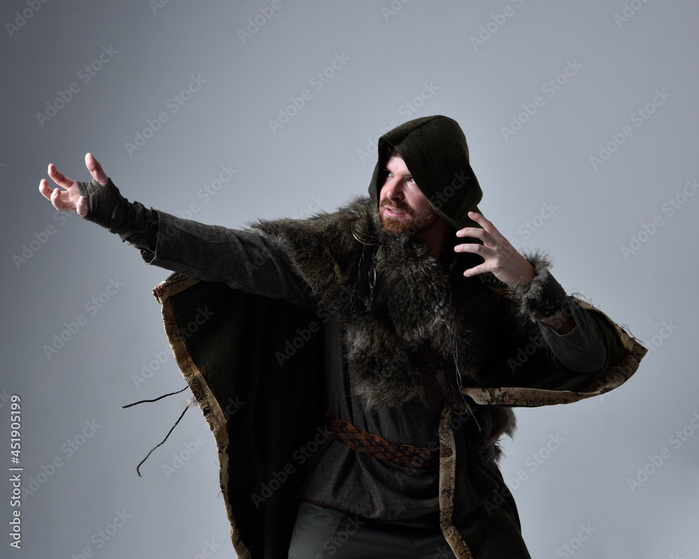 Φωτογραφία Close up  portrait of  young handsome man  wearing  medieval Celtic adventurer costume with hooded fur cloak,  isolated on studio background