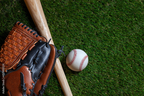 Baseball and wood bat with mitt on grass field overhead view photo