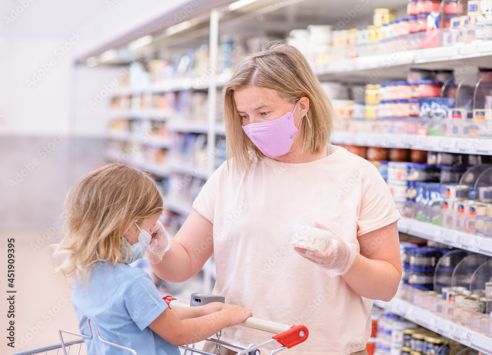 Mother and her little daughter wearing protective face mask shop a food at a supermarket during the coronavirus epidemic or flu outbreak Mother and her little daughter wearing protective face mask shop a food at a supermarket during the coronavirus epidemic or flu outbreak