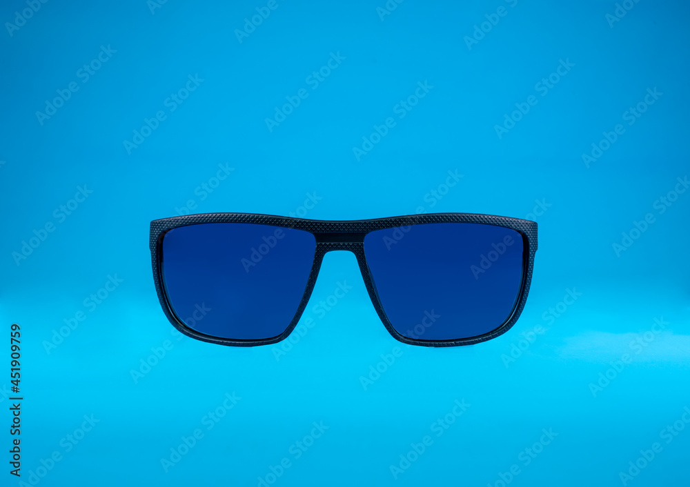 Sun Glasses with blue glass and black frame on blue background Sun Glasses with blue glass and black frame on blue background