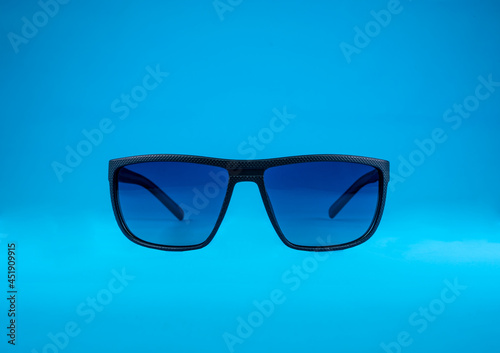 Sun Glasses with blue glass and black frame on blue background