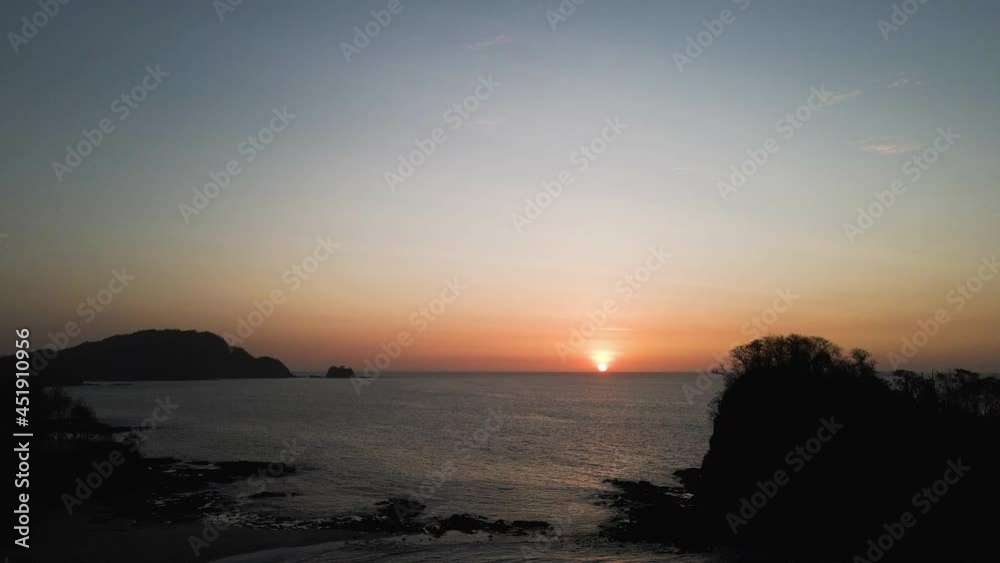 Orange Sunset In The Ocean From Pirates Bay Beach In Costa Rica. - aerial drone Orange Sunset In The Ocean From Pirates Bay Beach In Costa Rica. - aerial drone