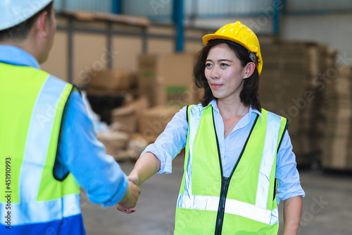 Factory employee of engineers, foreman, technicians and staff. Wear a mask, hard hat, and vest. shake hands to make a deal or celebrate success in the organization or warehouse. Teamwork concept.