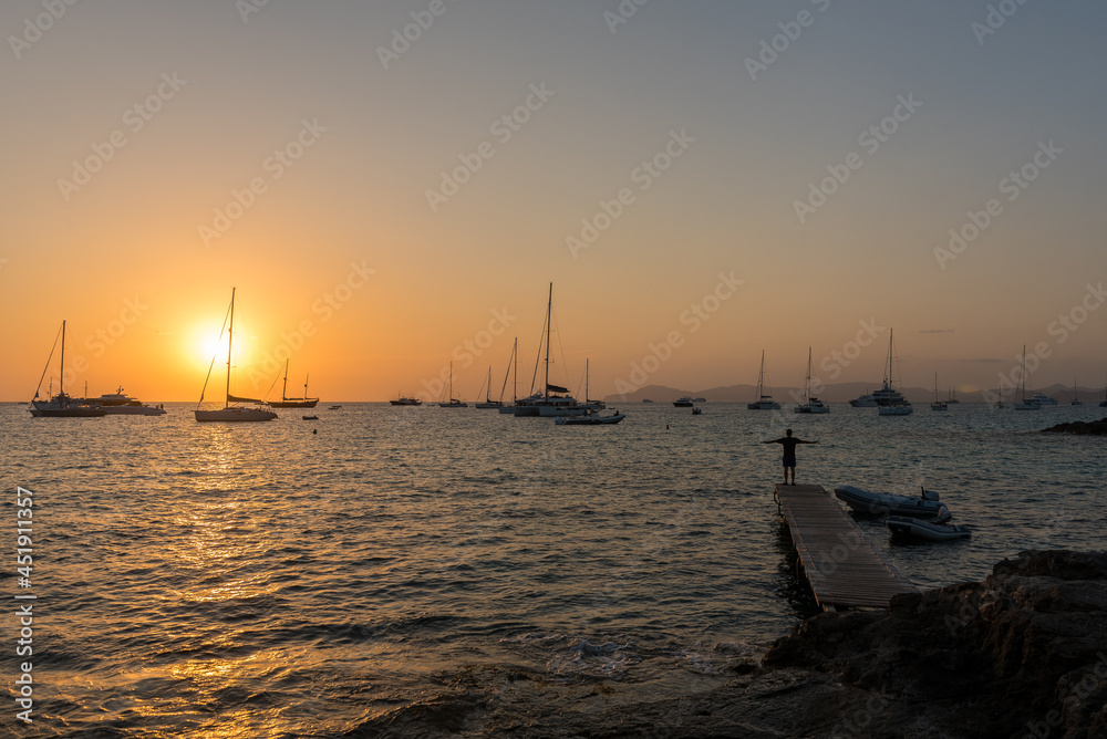 Men in the pier in the Sunset on the beach of Ses Illietes on the Island of Formentera in the summer of 2021