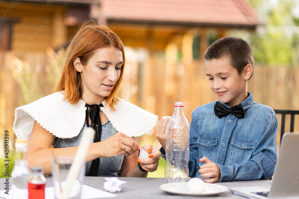 Mom and son are doing physical experiments at home. An experience with a child on how to place a boiled egg in the narrow neck of a plastic bottle using fire. Homemade creativity with a child Mom and son are doing physical experiments at home. An experience with a child on how to place a boiled egg in the narrow neck of a plastic bottle using fire. Homemade creativity with a child