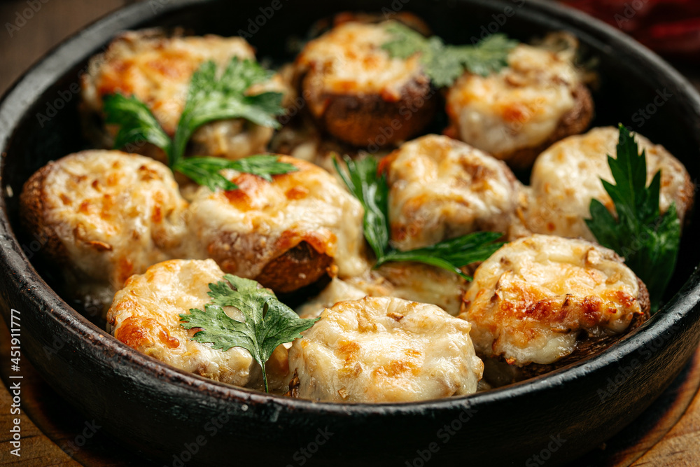 Georgian baked mushrooms with suluguni cheese on a wooden background