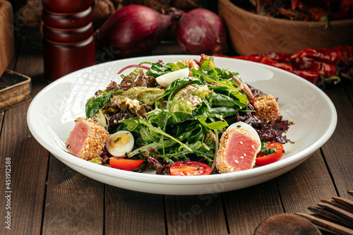 Mediterranean nitzard salad with roasted tuna on a wooden background