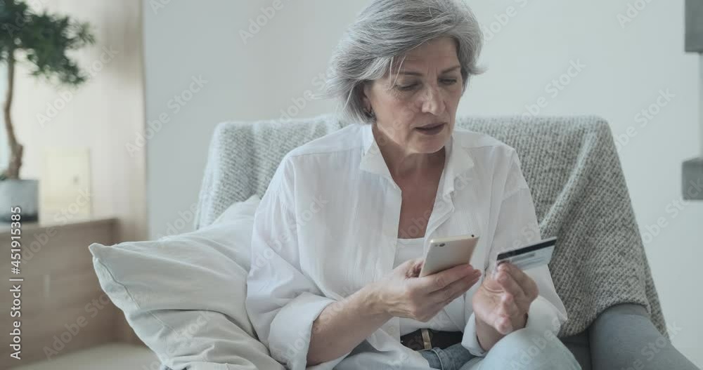 Caucasian senior woman using credit card and mobile phone for online shopping. Mature old retired female making purchase in internet stores. Instant ebanking. Elderly people's usage of technology Caucasian senior woman using credit card and mobile phone for online shopping. Mature old retired female making purchase in internet stores. Instant ebanking. Elderly people's usage of technology
