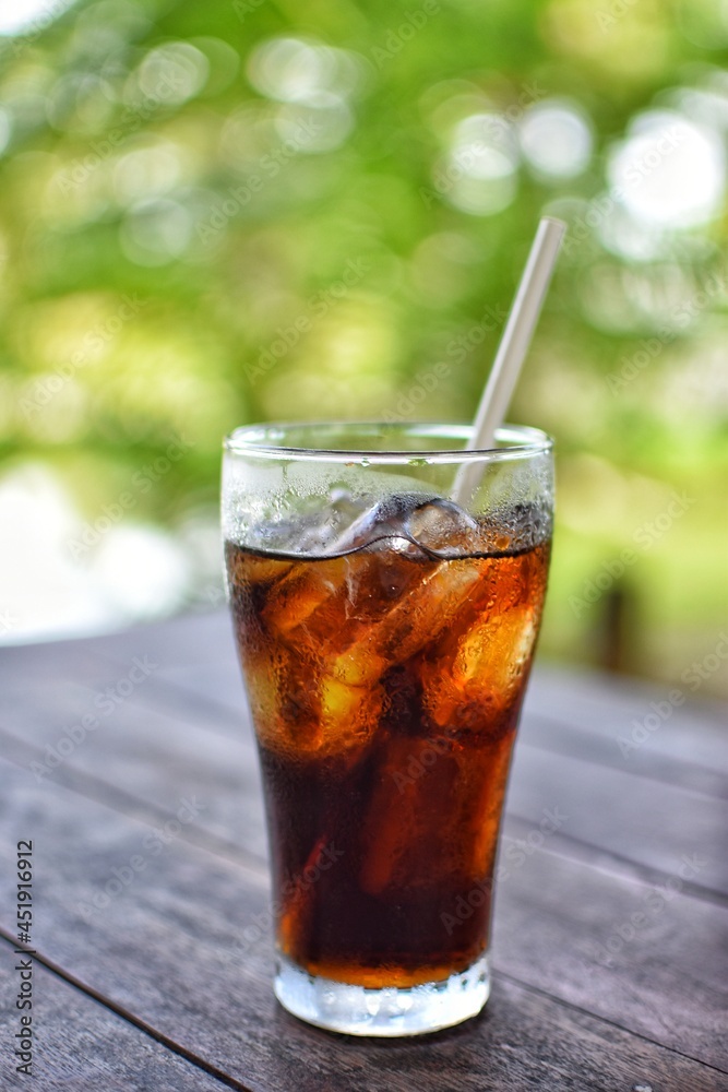 Cola drink on a wooden table and the blur background of green plant. Cola drink on a wooden table and the blur background of green plant.