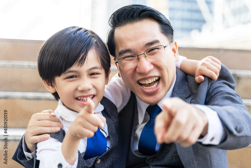 business man and his lovely son  They were both pointing fingers at something that made them both smile happily - Dad and Son happy Asian family concept