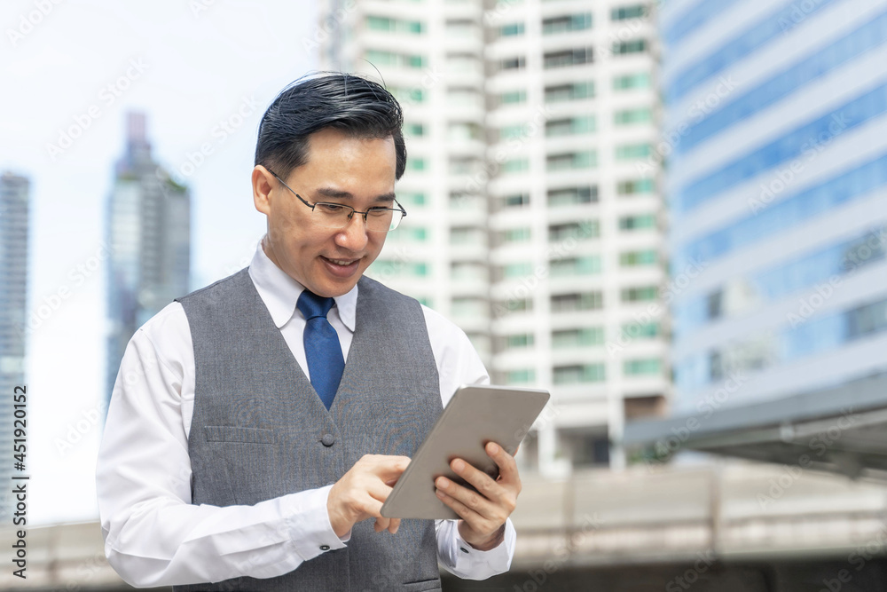 Business Asian man using tablet computer on business district urban - lifestyle business people concept Business Asian man using tablet computer on business district urban - lifestyle business people concept