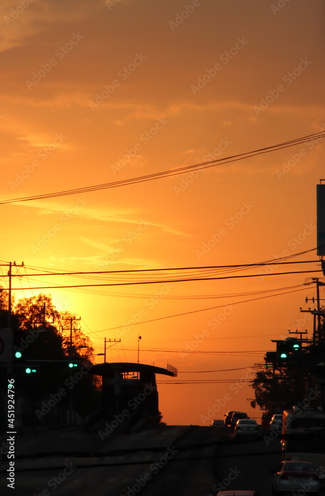 Atardecer con tonos rojos y naranjas en la ciudad con edificios y autos en sombras frente a la puesta de sol