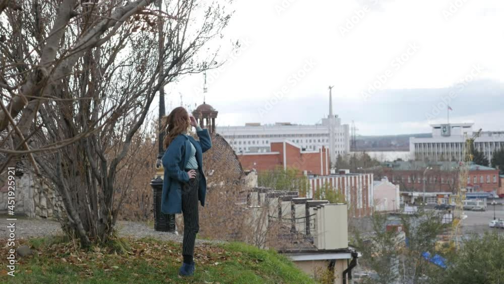 young red-haired woman in a blue coat and walks against the backdrop of the old city. portrait of a beautiful woman in the autumn city. young red-haired woman in a blue coat and walks against the backdrop of the old city. portrait of a beautiful woman in the autumn city.