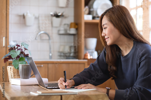 A beautiful young asian woman using laptop computer for working or studying online at home