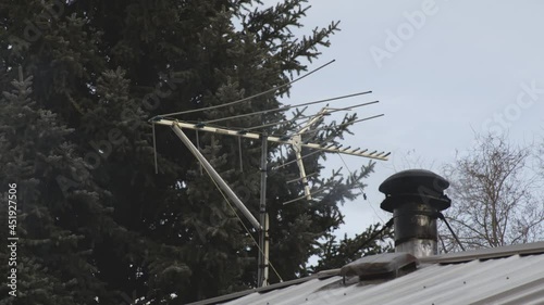 Television Antenna With Smoke Coming Out In Stove Chimney On A House Roof. - static photo