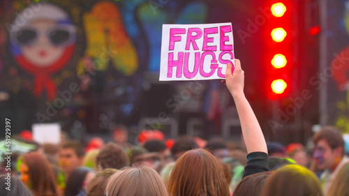 Foto young girl holds free hugs poster at concert and dance