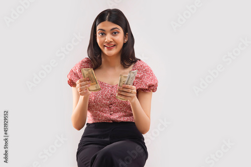 Fotografía Portait of a young woman sitting and counting 500 rupees Indian currency notes