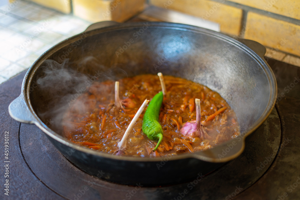A man prepares a pilaf in cauldron on street mangal A man prepares a pilaf in cauldron on street mangal