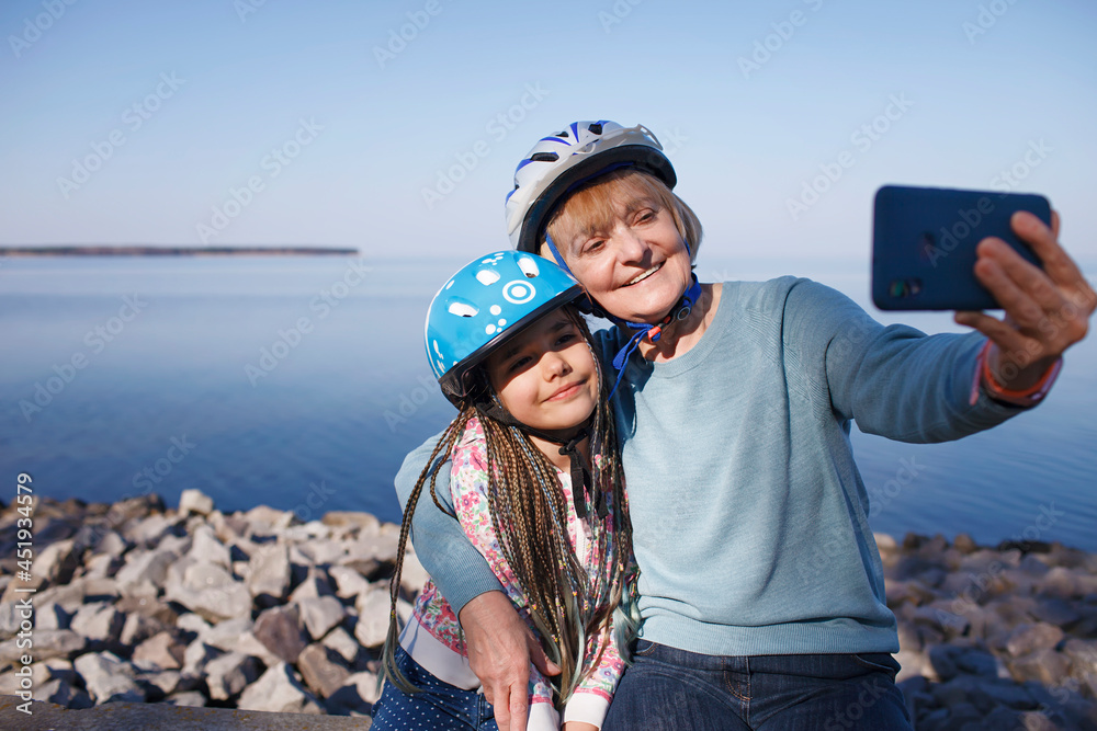 Happy senior woman taking selfie together with grandchild after riding on roller skates, hugs and support, family activity, spring or fall outdoors, healthy lifestyle - obrazy, fototapety, plakaty 
