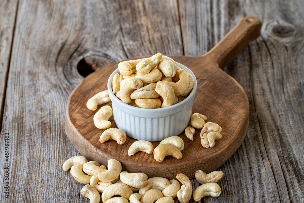 Roasted Cashews. Cashew nuts on wood background. Bulk Cashews. Cashew on ceramic plate
