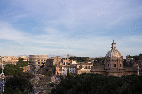 View of Rome from the Capitoline hill.Behind the trees, the Church of Santa Maria Aracoeli, the Colosseum against the background of the city and the sky